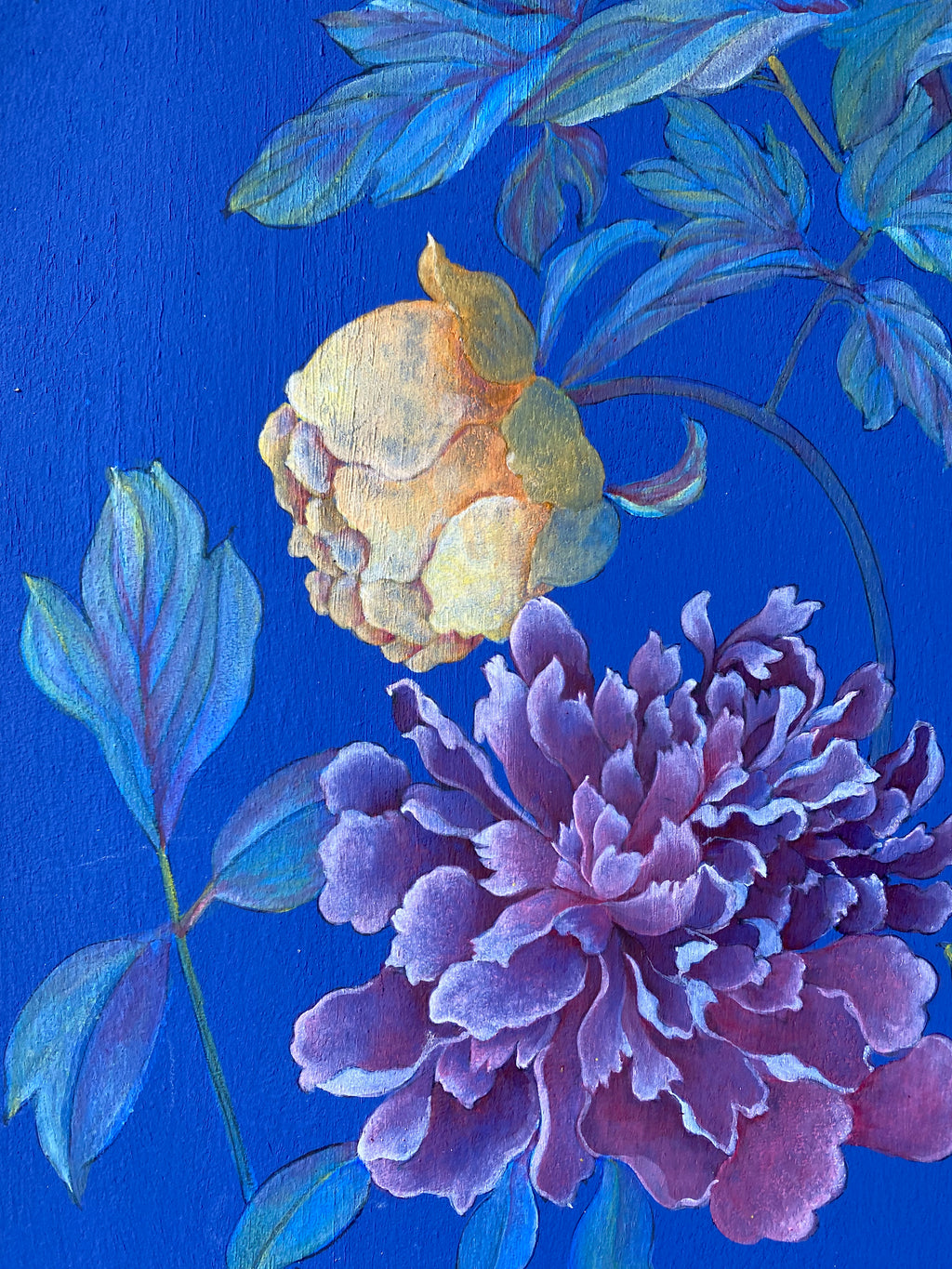 A close-up floral artwork showing a large purple flower with layered petals and a smaller pale yellow bud, surrounded by blue leaves on a vivid blue background.